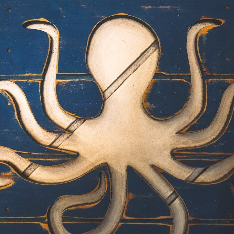 Detailed close-up of a wooden octopus sculpture on a blue panel, showcasing handcrafted artistry.